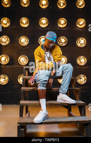 Black rapper in cap sitting on the steps Stock Photo