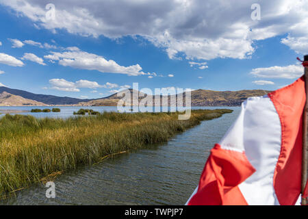 Red and white national flag flying on a boat in a channel through the totora reeds of Lake Titicaca, Peru, South America Stock Photo