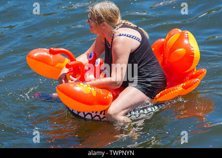 Iford, Dorset, UK. 22nd June 2019. Perfect weather, warm sunny and still, for Dorset Dinghy Day with hundreds of inflatables, dinghies, crafts, boards forming a flotilla, setting sail from Iford bridge down the River Stour to Tuckton bridge. The event started in 2014 as a little bit of fun, but has now become an annual event raising money for charity and getter bigger each year. Woman on inflatable lobster inflatable. Credit: Carolyn Jenkins/Alamy Live News Stock Photo