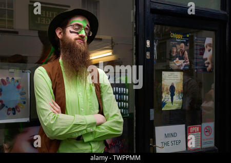 A Morris dancer is colourful clothes and sporting a full beard takes a  short rest between performances in Beverley, Yorkshire, UK. Stock Photo