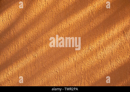 Orange colored rough wall texture with diagonal shadows. Stock Photo