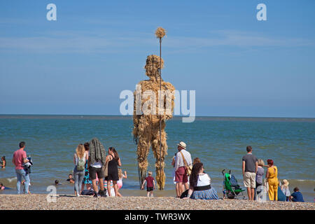 22nd June 2019. Lowestoft, England, UK. Lowestoft's First Light Festival, crowds gather on South Beach with temperatures of over 20 degrees with beautiful blue skies. Festival runs for 24 hours non-stop until 12 pm on Sunday. Visitors look at the straw Pakefield Man'. Arts charity FlipSide are delivering the festival in partnership with Hemingway Design. Visitors look at the straw Pakefield Man'. Stock Photo