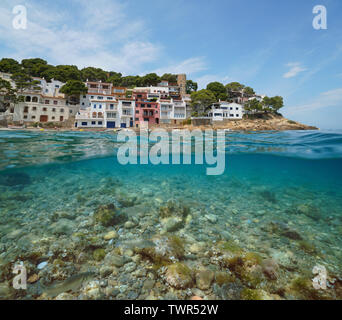 Coastline of Mediterranean village on Costa Brava in Spain with sea bass fish and rocks underwater, Sa Tuna, Begur, Catalonia, over and under water Stock Photo