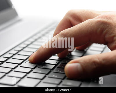 Closeup male hand typing keyboard computer laptop backlit Stock Photo