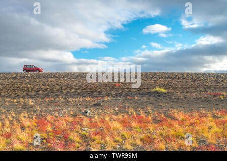 Distant red Fiat Panda 4x4 parked on a gravel road off the beaten path in Iceland. Commercial car picture of a small rental car during a road trip. Stock Photo