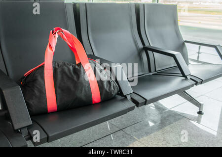 Suspicious black sport bag left on chairs unattended in the airport, train station. Lost luggage. Concept of safety in public places and terrorism. Da Stock Photo