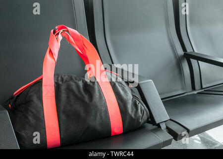 Suspicious black sport bag left on chairs unattended in the airport, train station. Lost luggage. Concept of safety in public places and terrorism. Da Stock Photo