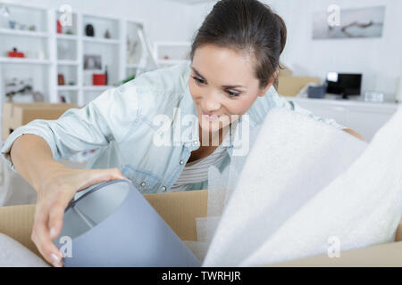 woman at home unpacking a lamp from a cardboard box