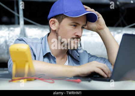 man testing electric current in circuit board of disassembled laptop Stock Photo