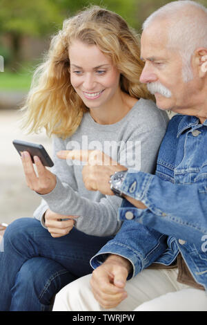 woman and his dad using a phone in the park Stock Photo