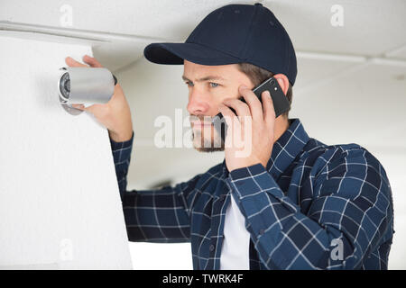 young technician encountering a problem while adjusting cctv camera Stock Photo