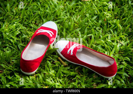 Red sneaker, Pretty woman wear jeans and a blue sneaker on a green meadow. Stock Photo