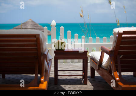 Two beach chairs facing the beach and ocean with a coconut drink in the middle on a nice sunny day Stock Photo