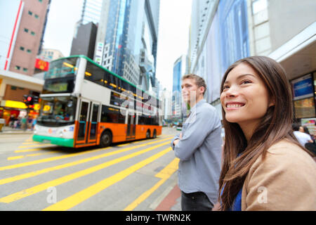 Hong Kong People walking in Causeway Bay crossing busy road with double decker bus. Urban mixed race Asian Chinese / Caucasian woman smiling happy living in city. Stock Photo