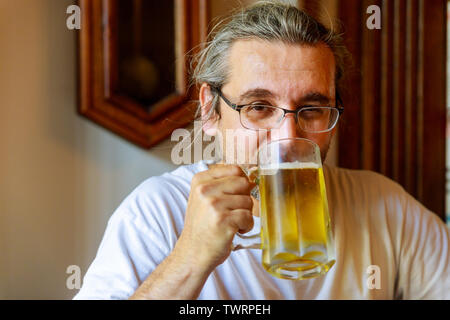Cropped image of handsome man is drinking beer in bar Stock Photo