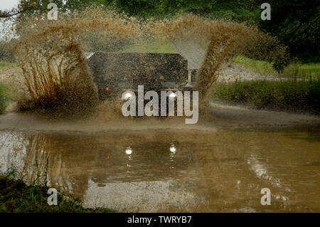 U.S. Soldiers from the 982nd Signal Company (Combat Camera) (Airborne) drive through a mud-puddle in a High Mobility Multipurpose Wheeled Vehicle (HMMWV) as part of their military driver’s license certification on Joint Base McGuire-Dix-Lakehurst, New Jersey 16 Jun, 2019. CSTX 78-19-02 is a Combat Support Training Exercise that ensures Army Reserve units are trained and ready to deploy on short-notice and bring capable, combat-ready, and lethal firepower in support of the Army and our joint partners anywhere in the world.  (U.S. Army photo by Spc. Anton Soukup) Stock Photo