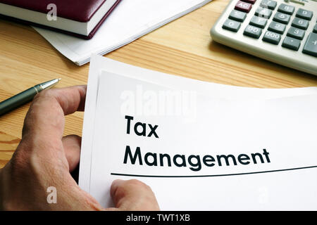 Man is holding Tax Management documents. Stock Photo