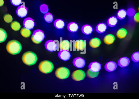 Purple green neon blurry bokeh lights. Festive winter background. Stock Photo