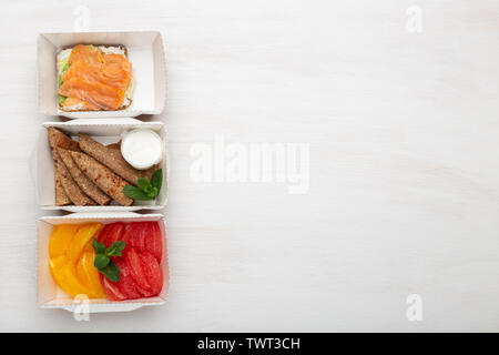 Three types of snack sandwich and pancakes and oranges with grapefruit are in a lunch box on a white table. Healthy eating concept. Advertising space. Stock Photo