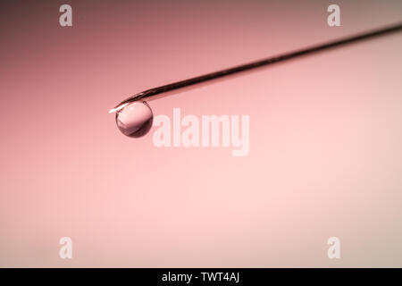 drop on the tip of needle - red background Stock Photo