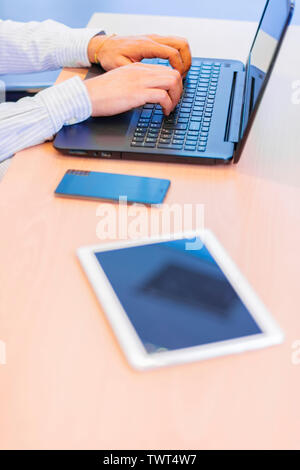 Businessman working at the office writing on his laptop with a smartphone and a digital tablet on the table Stock Photo