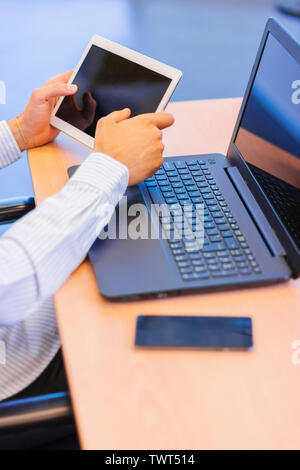 Businessman working at the office with his digital tablet with a laptop and a smartphone on the table Stock Photo