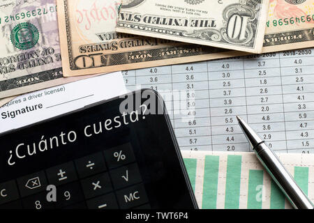 Calculator with How much? text in Spanish, document with place for signature, charts and US dollars on the background. Goals, plannings, shopping conc Stock Photo