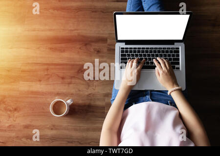 top view of woman typing on laptop computer with blank white screen from home on wooden floor with copy space Stock Photo