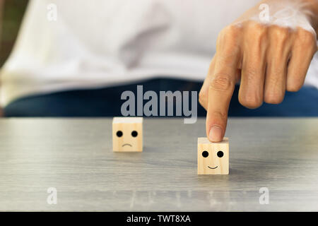 Conceptual the customer responded to the survey. The client using hand choose happy face smile icon on wood block. Depicts that customer is very satis Stock Photo