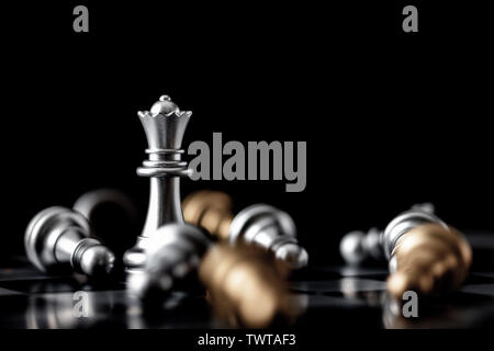 Queen standing in the midst of falling gold and silver chess on board Stock Photo