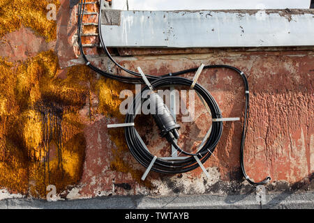 spool of long black wire on the roof of a house somewhere in russia. Stock Photo