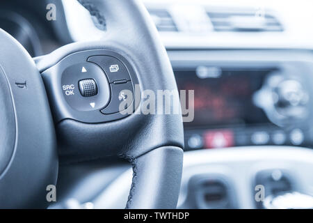Close up of a steering wheel with remote control, blurry dashboard Stock Photo