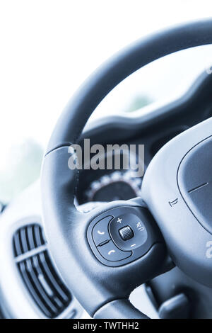 Close up of a steering wheel with remote control, blurry dashboard Stock Photo