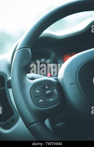 Close up of a steering wheel with remote control, blurry dashboard Stock Photo