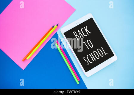 Colorful paper, neon pencils and tablet on blue and pink background with text space. Back to school concept. Stock Photo