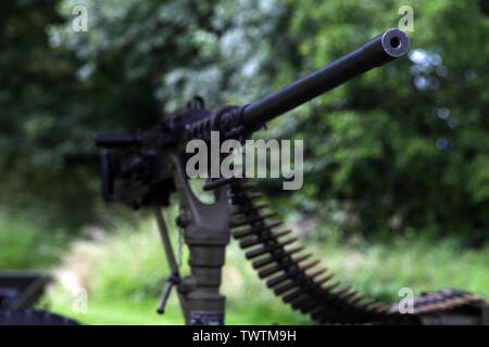 Mounted M2 Browning .50 caliber machine gun with tip in focus and bullets with natural green background Stock Photo