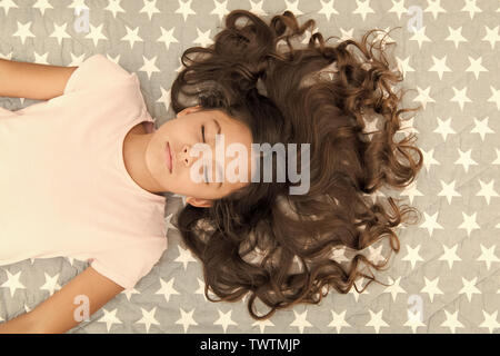 Kid perfect curly hairstyle. Conditioner mask organic oil keep hair shiny and healthy. Amazing curls tips. Make it curly but natural. Girl long curly hair lay top view. How take care of hair at night. Stock Photo