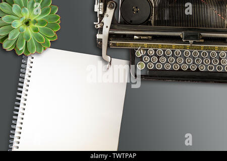 top view of blank open spiral-bound notepad, old typewriter and succulent plant on desk Stock Photo