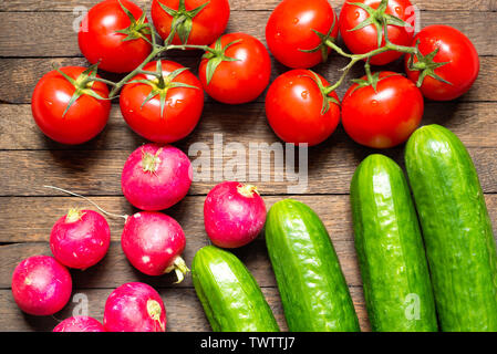 Harvested washed vegetables. Agriculture background. Tomatoes, radishes and cucumbers on wooden table. Fresh raw food. Three groups of objects. Health