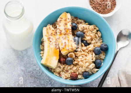 Oatmeal with banana, blueberries, flax seeds and hazelnuts. Healthy tasty nutritious breakfast. Top view, closeup Stock Photo