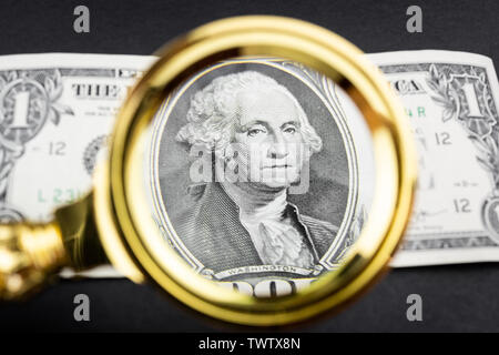magnifying glass lies on american dollars on black background Stock Photo