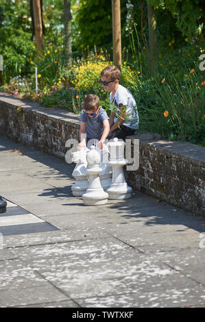 A Family enjoying a game of giant garden chess in the summer sunshine at Burton Agnes Hall, East Yorkshire, UK, GB. Stock Photo