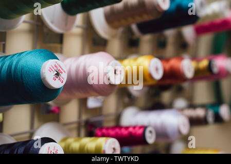 Spools of thread hanging in a tailor shop. Skeins for sewing machine hang in a sewing shop. close photo. Stock Photo