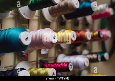Spools of thread hanging in a tailor shop. Skeins for sewing machine hang in a sewing shop. close photo. Stock Photo