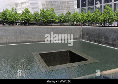 New York City, USA - June 05, 2019: People standing on the edges of National September 11 Memorial and Museum and observing square reflecting pools. Stock Photo
