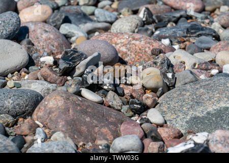 Multi coloured pebbles on a beach in bright sunshine Stock Photo