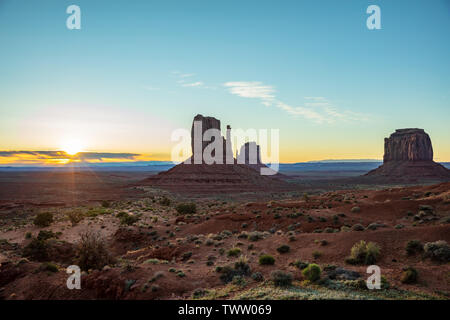 Monument Valley at sunrise. Navajo Tribal Park in the Arizona-Utah border USA. Sun rising behind the red rocks, clear sky background