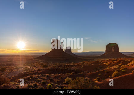 Monument Valley at sunrise. Navajo Tribal Park in the Arizona-Utah border USA. Sun rising behind the red rocks, clear sky background