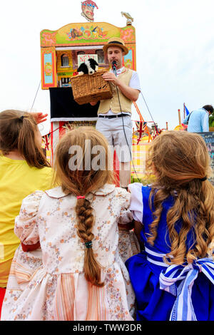 Broadstairs Dickens festival. View over the shoulder of young children in Victorian era Dickensian costume watching a Punch and Judy show outdoors. Stock Photo