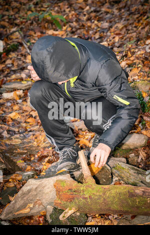 Boy in rain gear looking in a creek for salalmanders in the Great Smoky Mountains National Park. Stock Photo